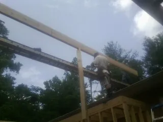 Carpenter setting a ridge beam over a new addition frame — Ice Dam Removal by Roofing Brothers in Shickley