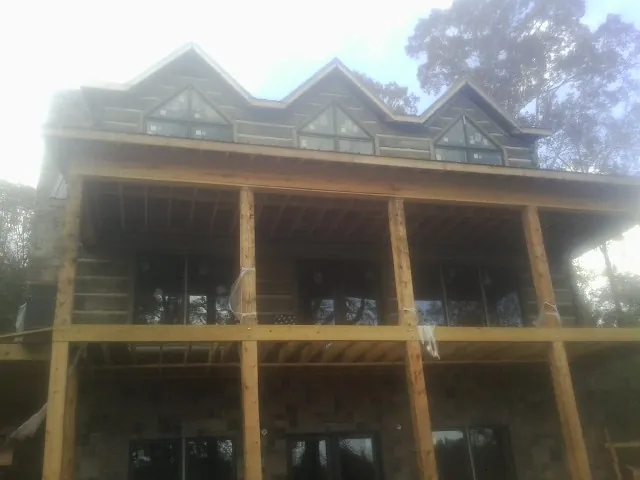 Dormers and porch framing on a large log home under construction — Roof Coating work by our crew in Shickley