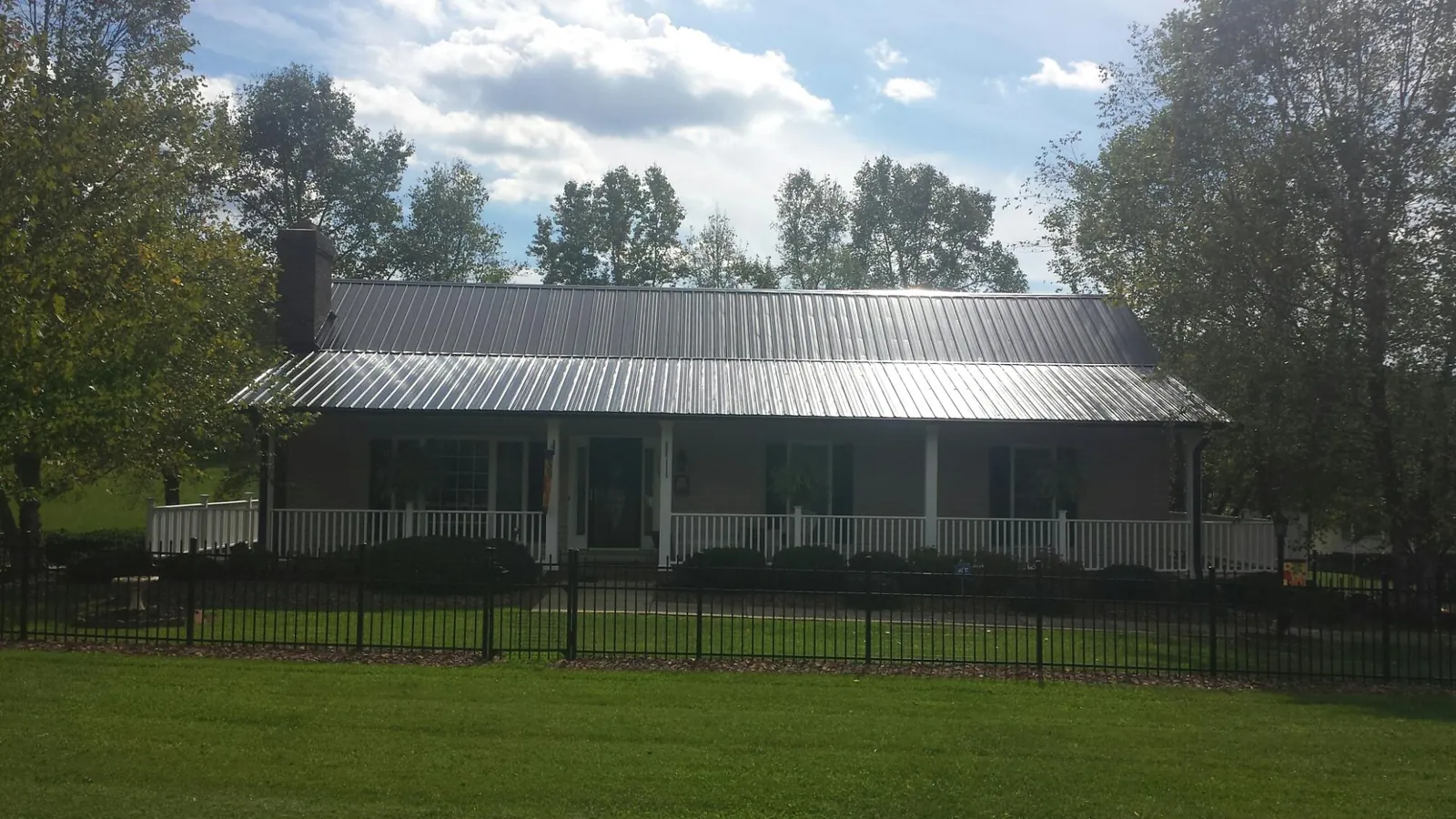 Gray metal roof on a brick ranch with a full width front porch — Gutter Guard Installation work by our crew in Shickley