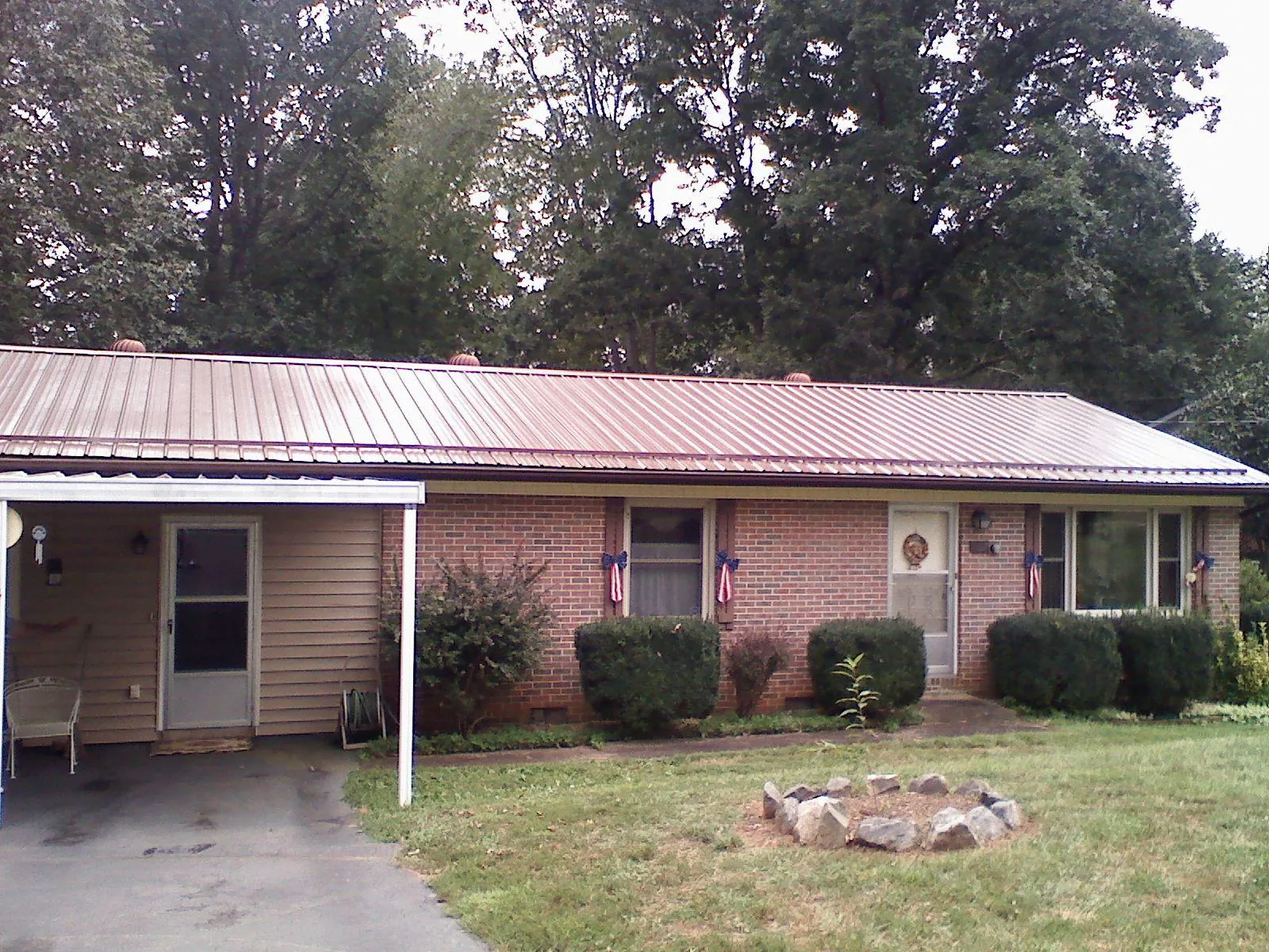 Bronze metal roof and carport on a brick ranch home — Roof Repair work by our crew in Shickley