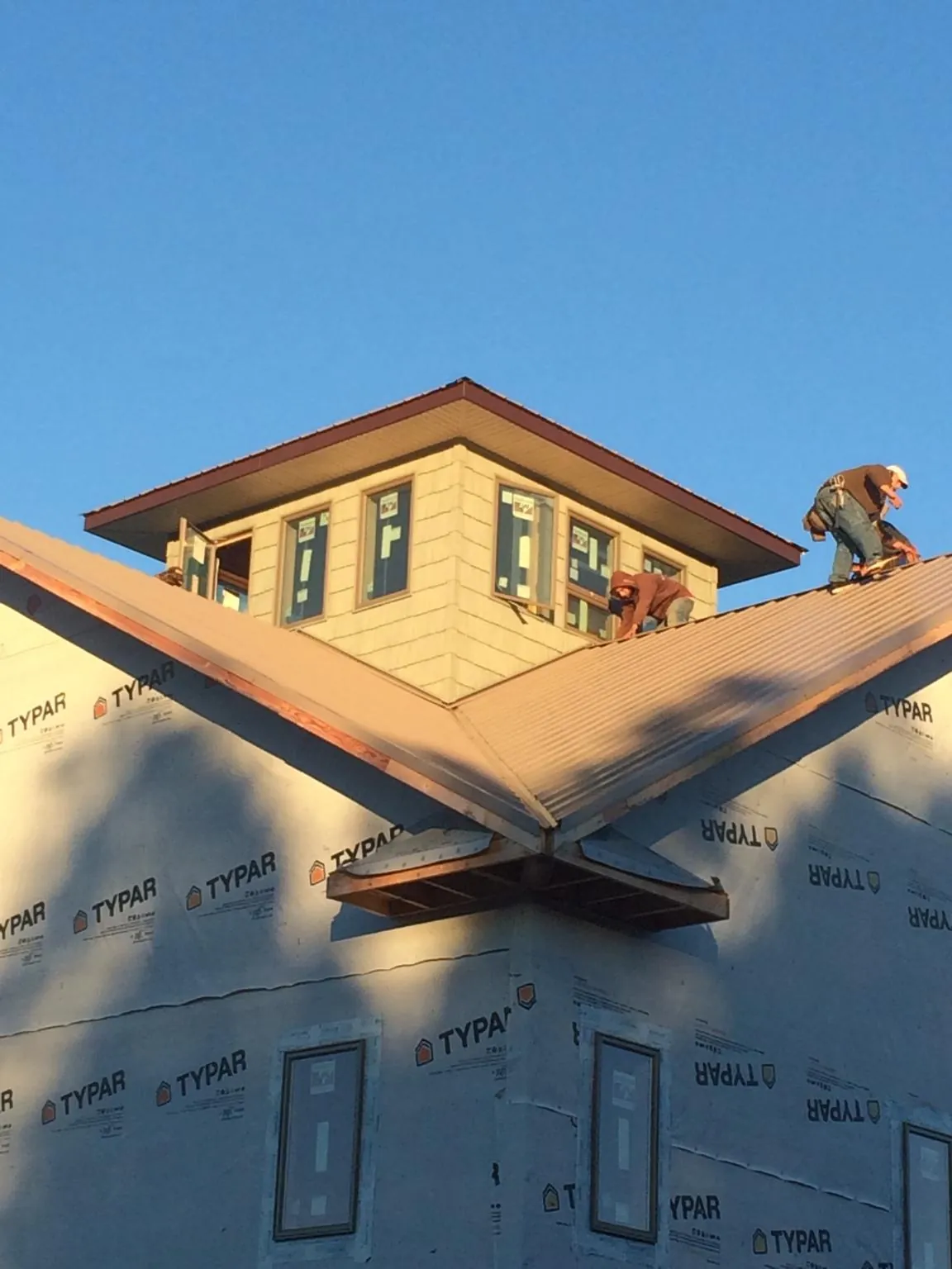 Roofers working around a rooftop cupola on a new metal roof at sunset — Roof Waterproofing in Shickley by Roofing Brothers